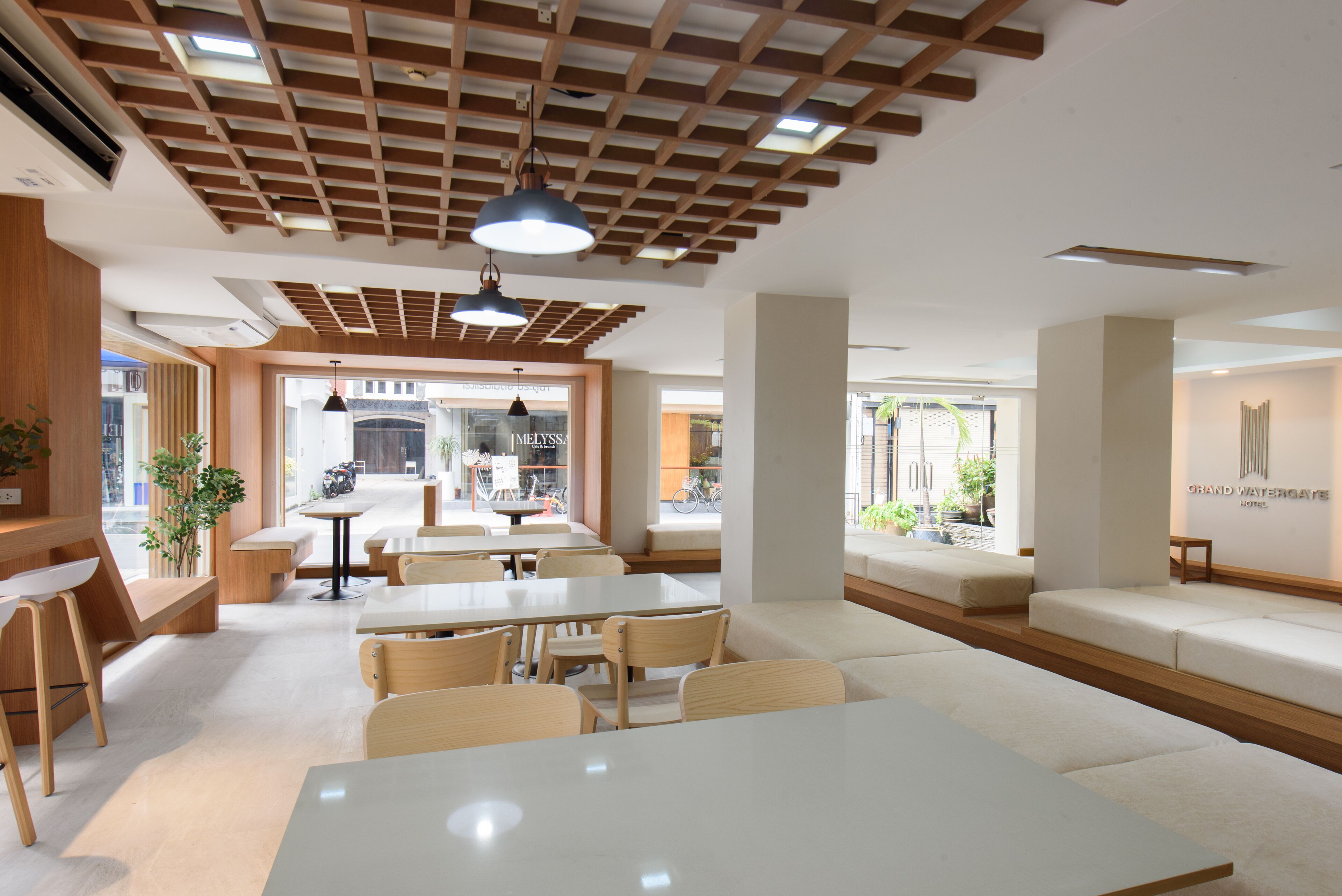 Un café moderne avec des tables et des bancs en bois, de grandes fenêtres et une vue sur la rue.