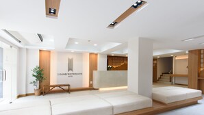 Un moderno vestíbulo de hotel con una recepción, zona de estar y una escalera.