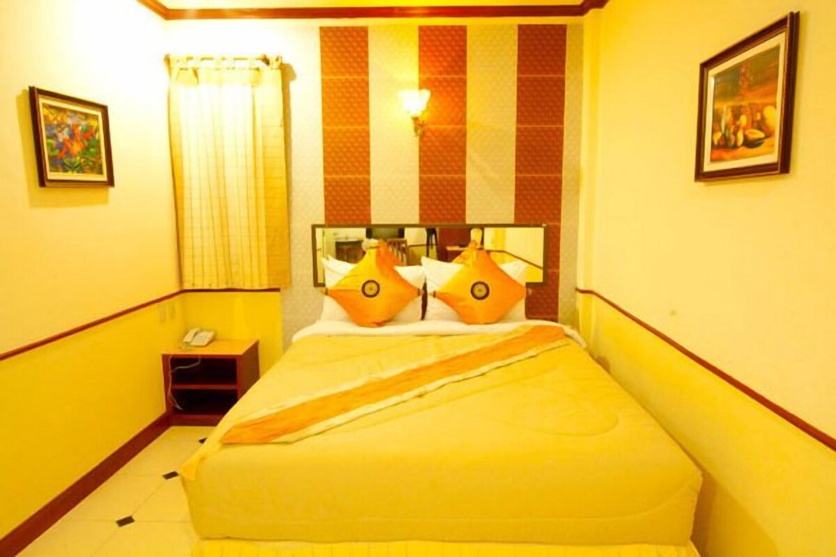 A hotel room with a bed, a nightstand, a mirror, and a painting on the wall.