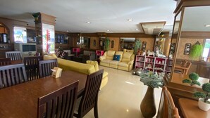 A spacious living area with a dining table and chairs, a yellow sofa, and a bookshelf. - Honey House 2 (Bangkok)