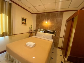 A hotel room with a neatly made bed, a vase with flowers, a framed picture on the wall, and a tiled floor. - Honey House 2 (Bangkok)