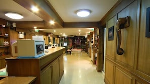 A hotel lobby with a reception desk, wooden paneling, and a tiled floor. - Honey House 2 (Bangkok)