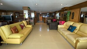 A spacious lobby with two leather sofas, a reception desk, and a television. - Honey House 2 (Bangkok)