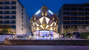 A modern building with a geometric facade and a pool area with lounge chairs. - Rodina Beach Hotel (Pattaya)