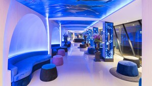 A hallway with a blue whale mural on the ceiling, seating areas, and potted plants. - Rodina Beach Hotel (Pattaya)