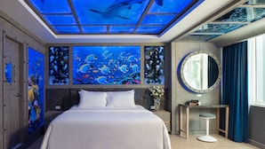 A modern hotel room with a large bed, a round mirror, and artwork depicting marine life. - Rodina Beach Hotel (Pattaya)
