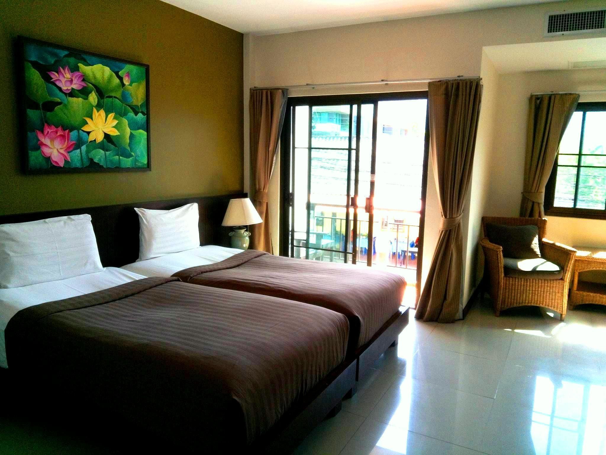 Habitación de hotel con una cama grande, una silla, una mesa y un cuadro de flores en la pared.