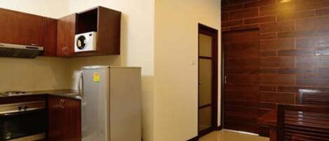 A compact kitchen with wooden cabinets, a stainless steel refrigerator, and a microwave.