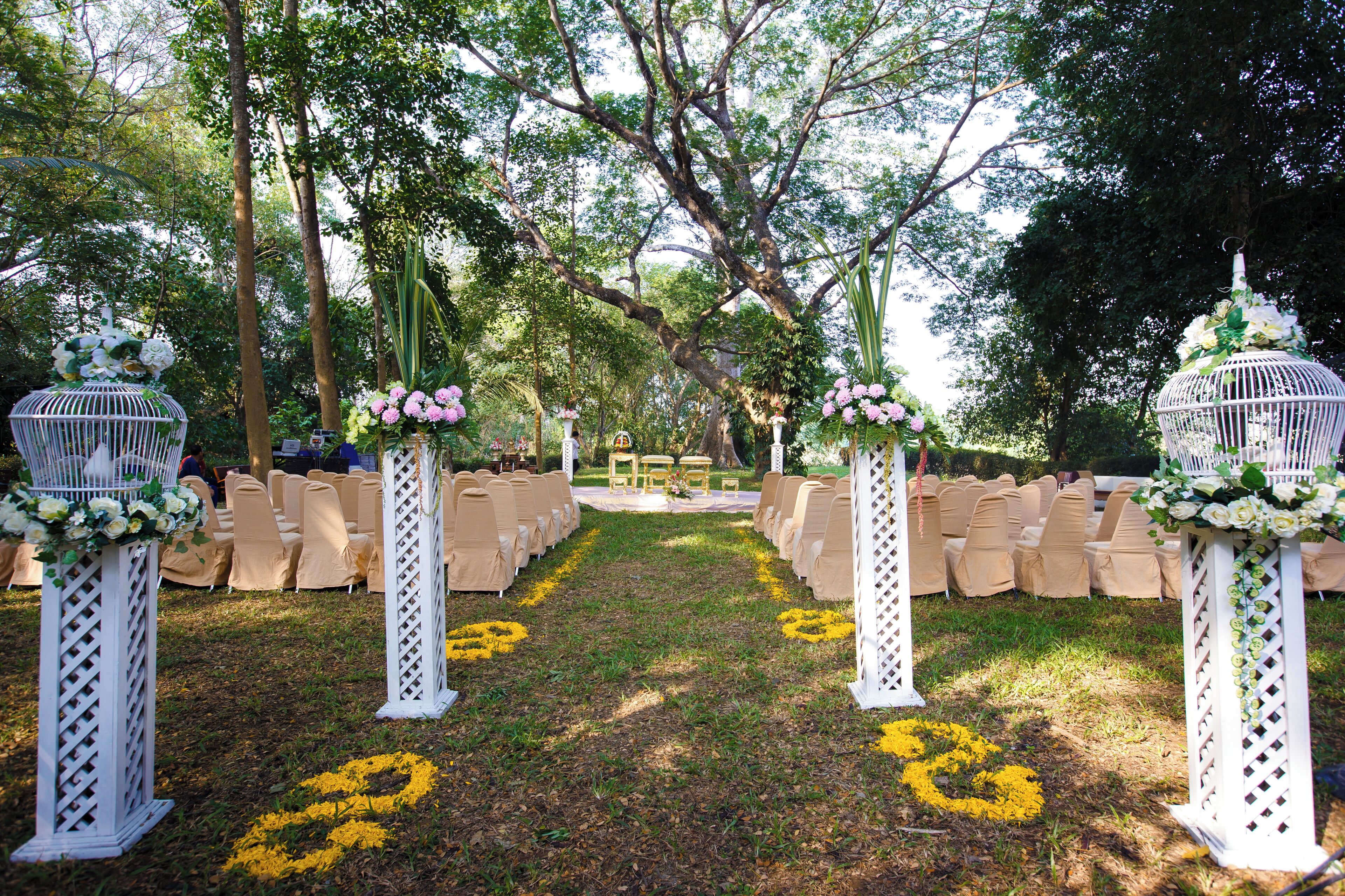 An outdoor wedding aisle with white chairs and floral decorations.