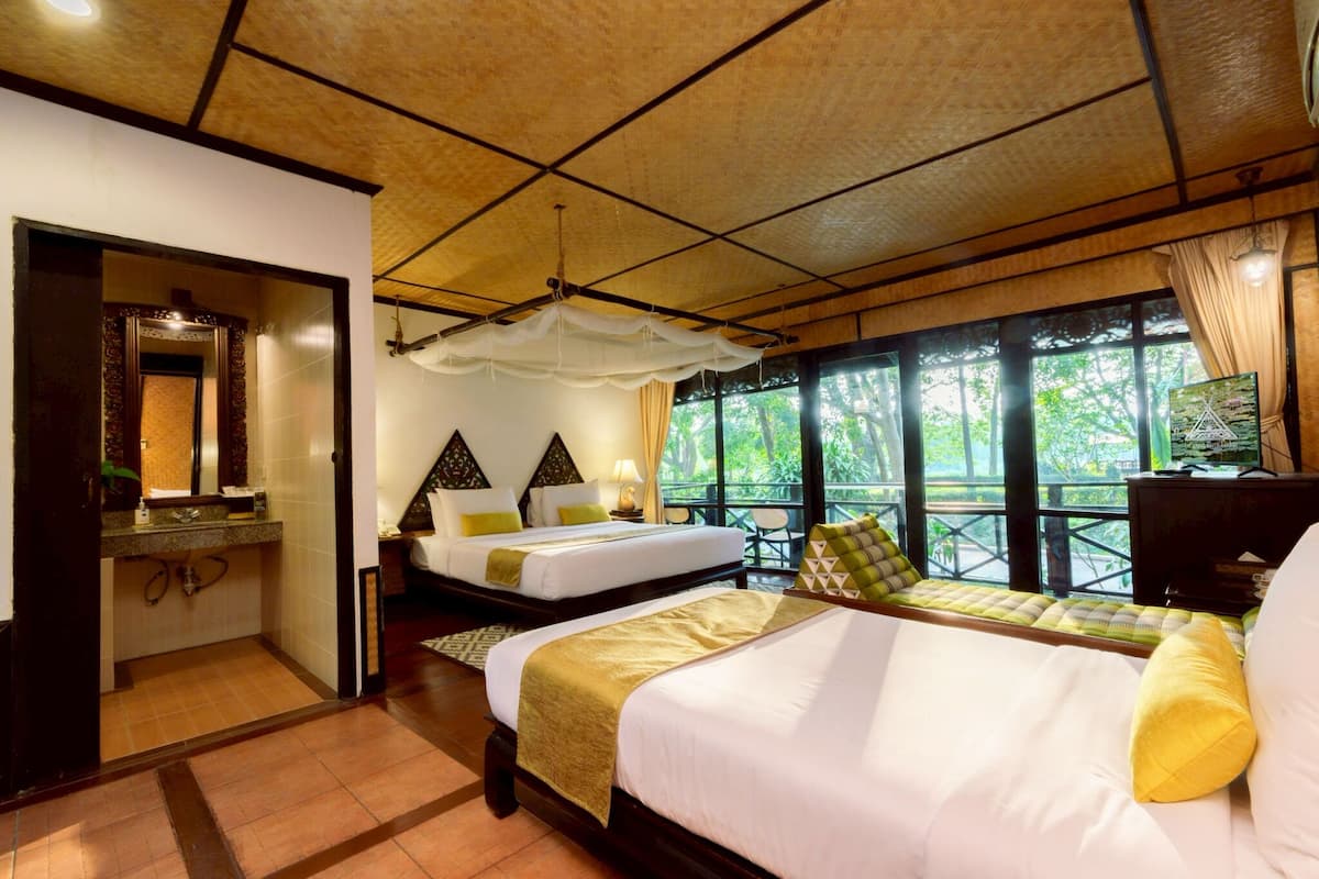 A hotel room with two beds, a bathroom, and a balcony with a view.