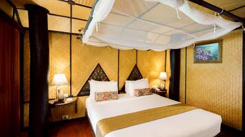 A hotel room with a bed, nightstands, a lamp, a canopy, and a painting on the wall.