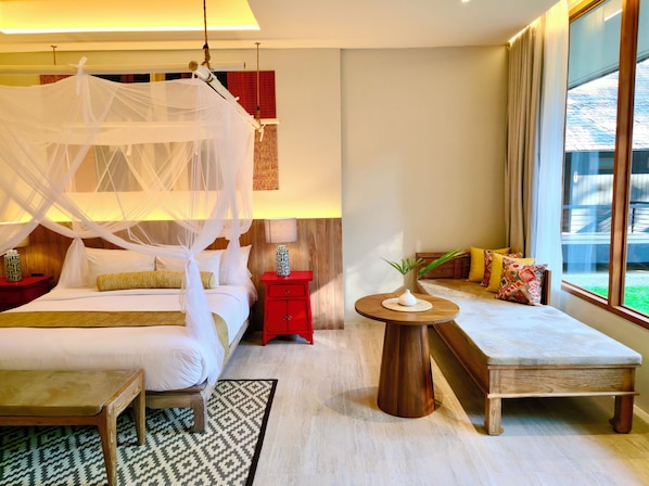 Un dormitorio con cama con dosel, una mesita de noche con lámpara, una pequeña mesa de madera y un banco con cojines.