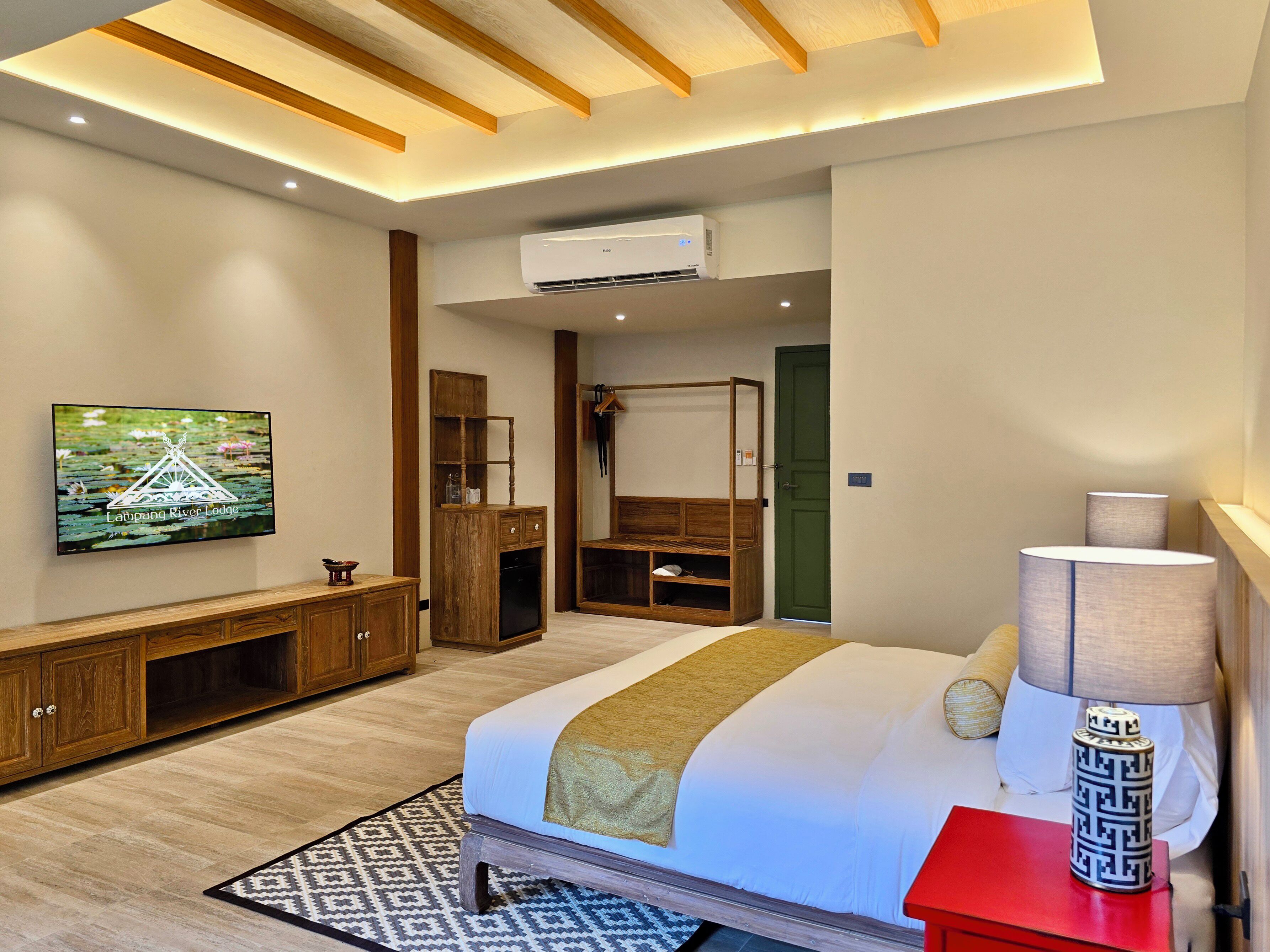 Ein modernes Hotelzimmer mit Bett, Fernseher, Kleiderschrank und Schreibtisch.