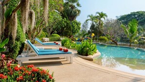 Zona de piscina con sillones de descanso y una pileta rodeada de exuberante vegetación.