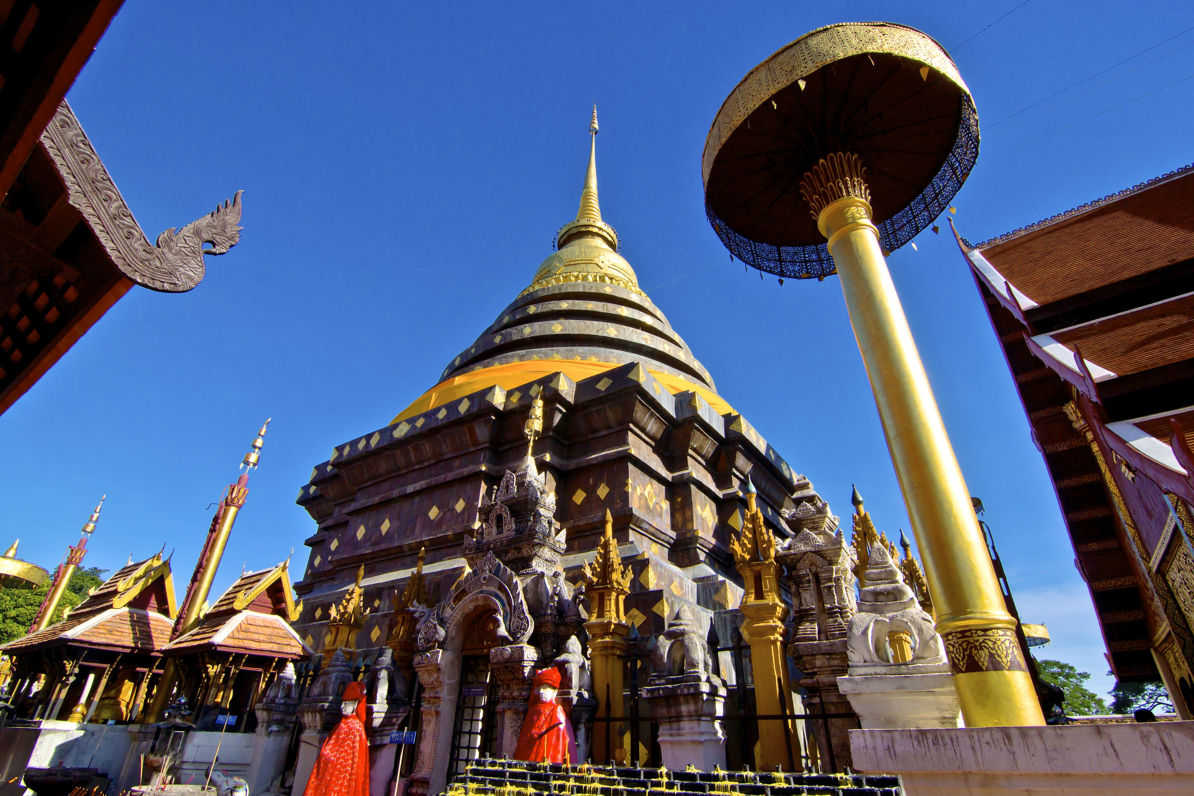A traditional temple with a large golden spire, intricate carvings, and a prominent golden column.