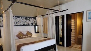 Un dormitorio espacioso con una cama grande, un dosel y vista al baño a través de una puerta abierta.
