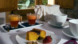 A breakfast setup with a plate of food, two glasses of juice, and a cup of tea on a table with a view of a mountainous landscape. -  Hospedería Bajo el Cejo  (Alhama de Murcia)