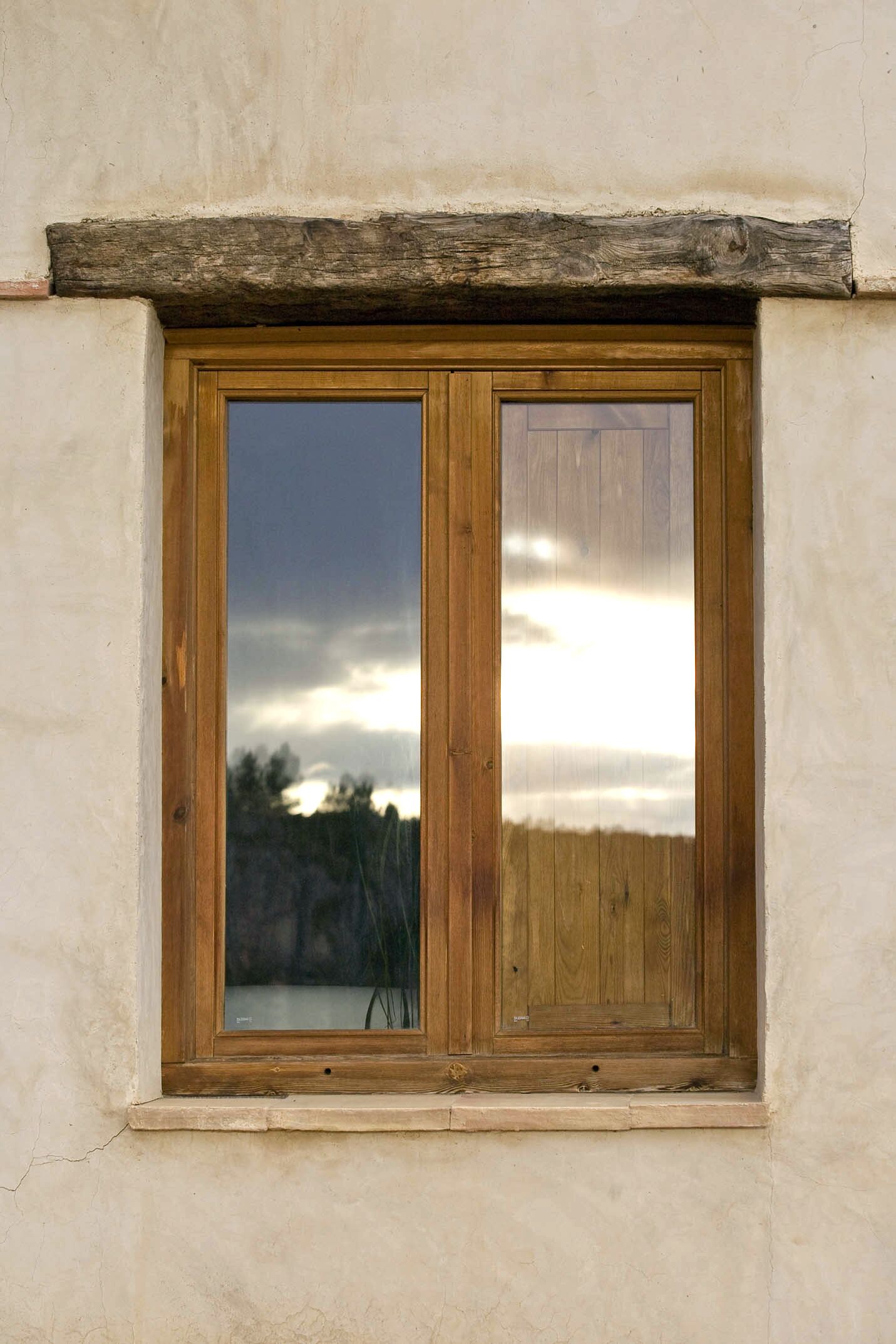 A window with a wooden frame and a view of a cloudy sky.