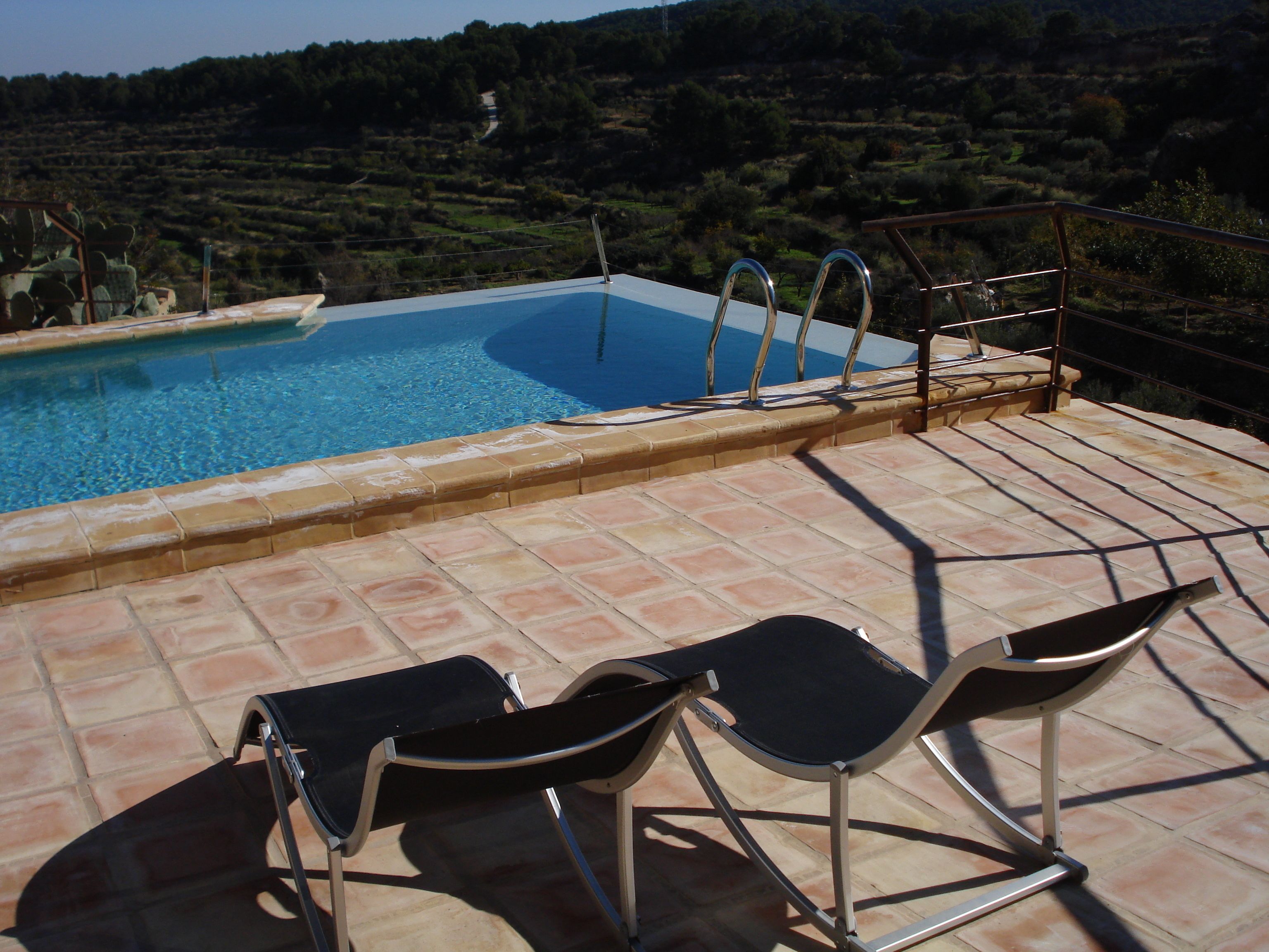 Een buitenzwembad, ligstoelen bij het zwembad