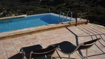 Een buitenzwembad, ligstoelen bij het zwembad