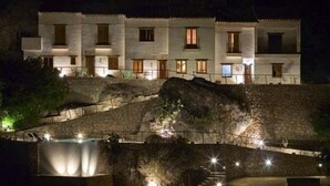 A multi-story building with a stone facade, multiple windows, and a staircase leading to a lower level. -  Hospedería Bajo el Cejo  (Alhama de Murcia)