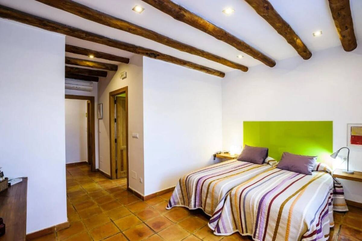 A bedroom with a bed, a nightstand, a lamp, and a green accent wall.