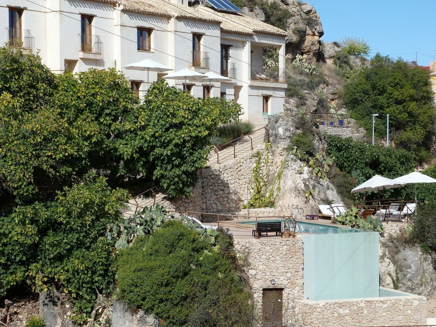 Un edificio blanco con balcones, piscina y mobiliario exterior.