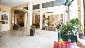A spacious indoor area with a high ceiling, stone walls, and multiple seating areas. - Safestay Athens Monastiraki (Athens)