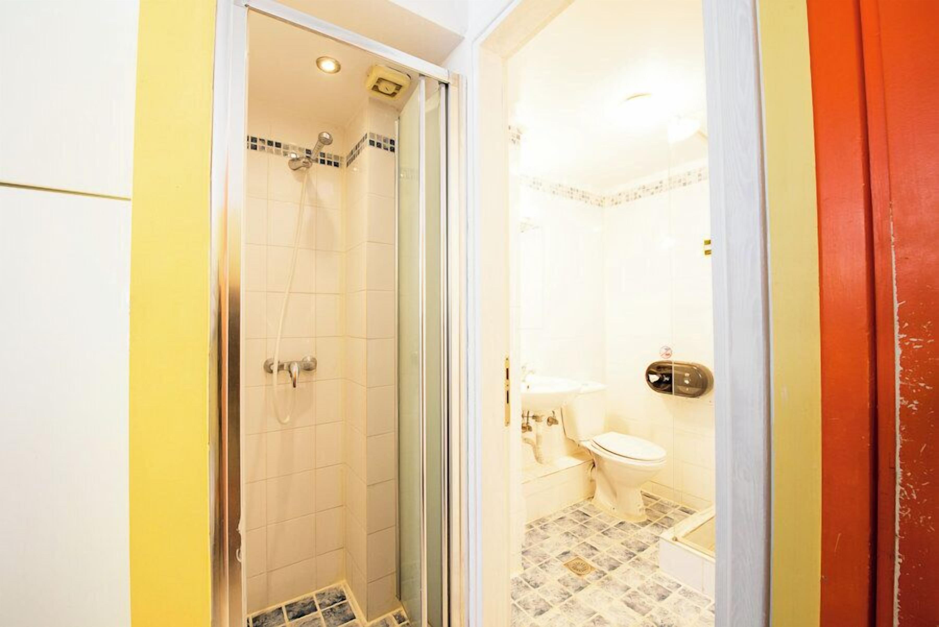 A bathroom with a glass-enclosed shower, a toilet, and a sink.