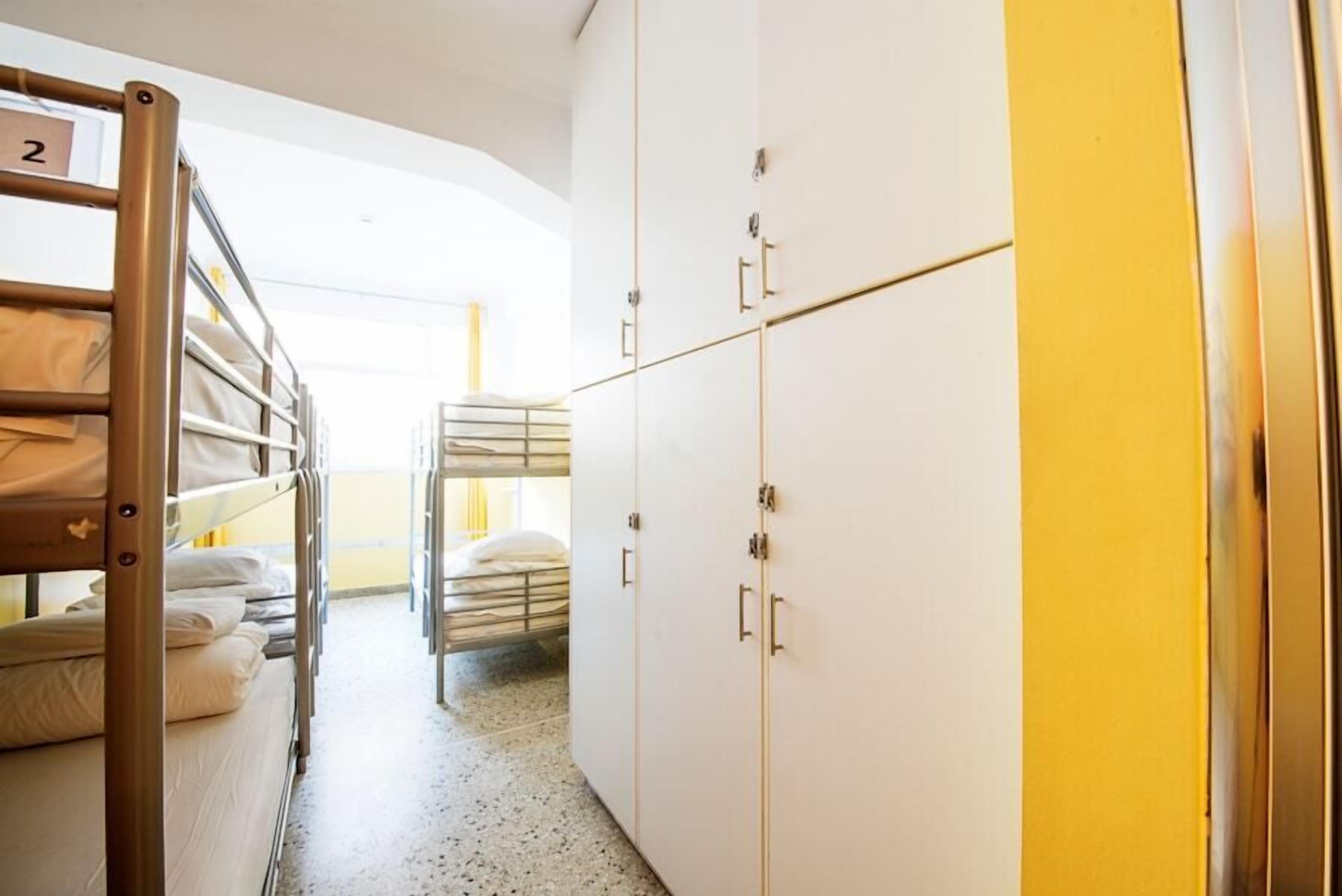 A hotel room with bunk beds, a wardrobe with multiple doors, and a hallway leading to another room.