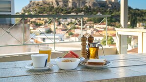 A balcony table with a cup, bowl, plate, and a pitcher of drink, overlooking a historic building. - Safestay Athens Monastiraki (Athens)