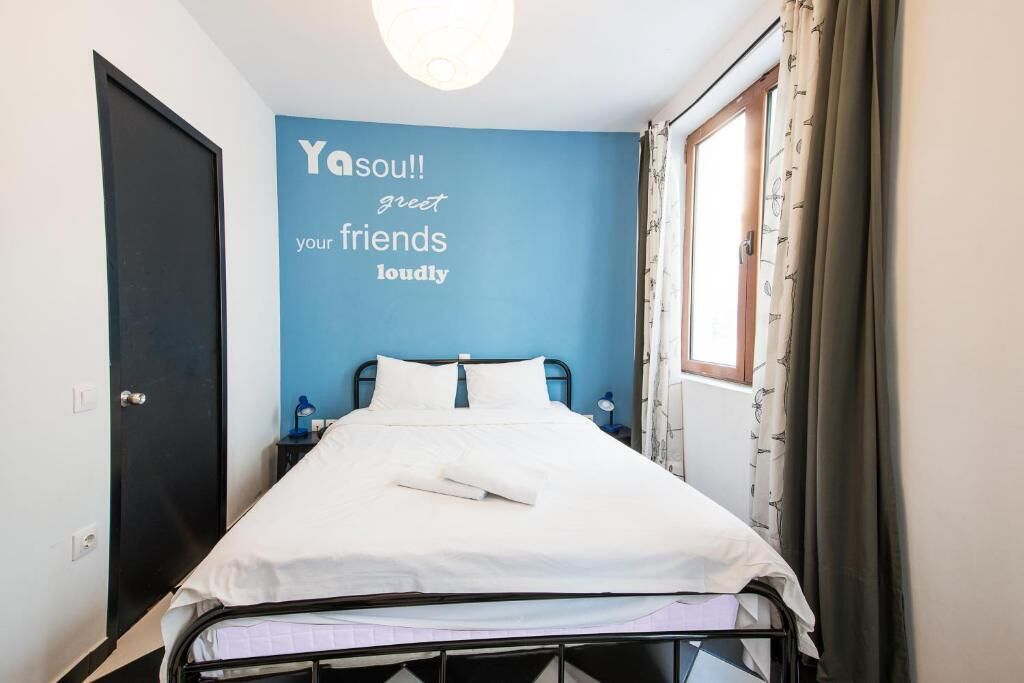 Ein Einzelbett in einem Zimmer mit blauer Akzentwand und einem motivierenden Zitat.