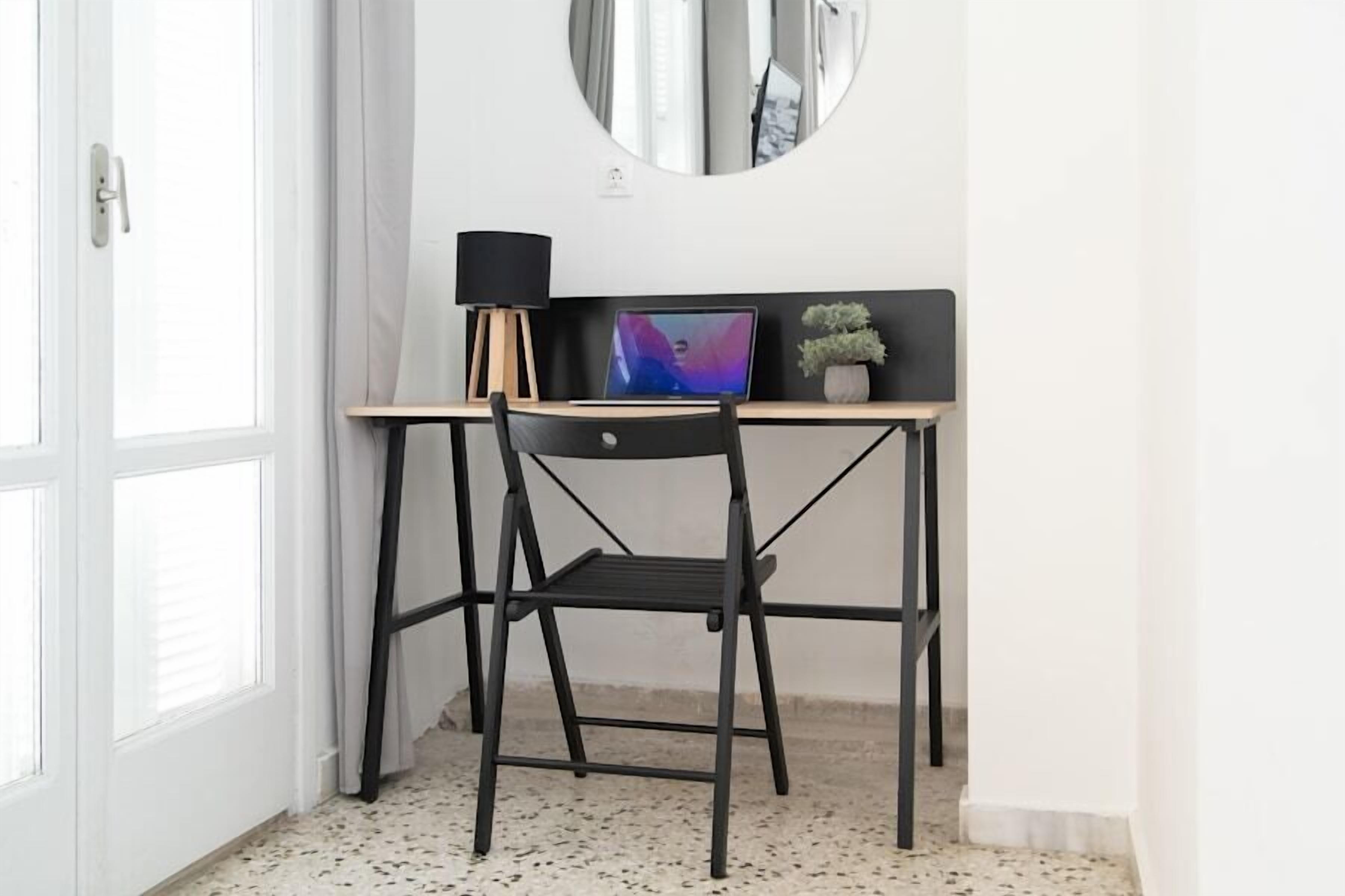 A compact workspace with a desk, chair, and a round mirror on the wall.