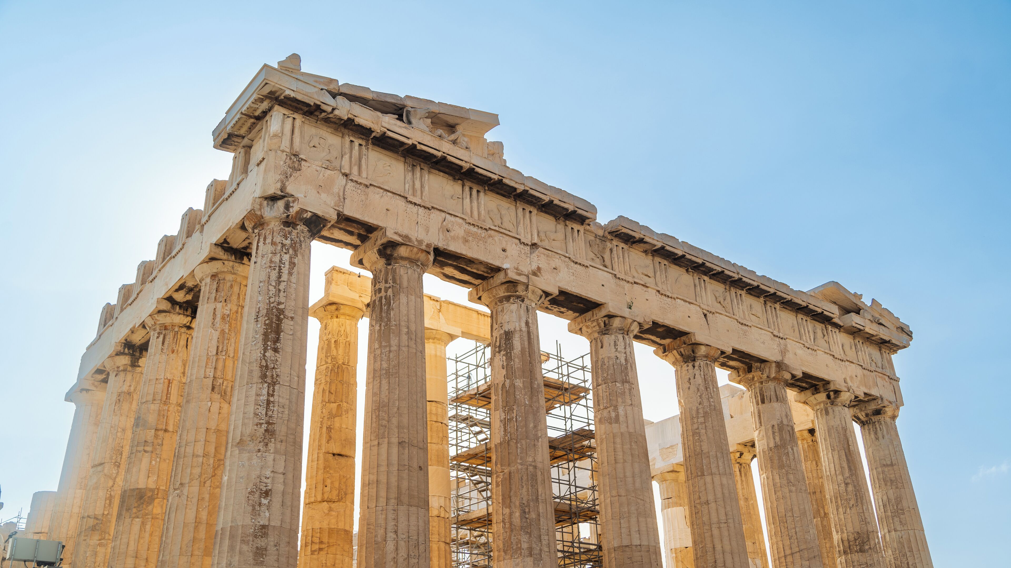 Il tempio del Partenone con le sue colonne doriche classiche e un cielo azzurro intenso.