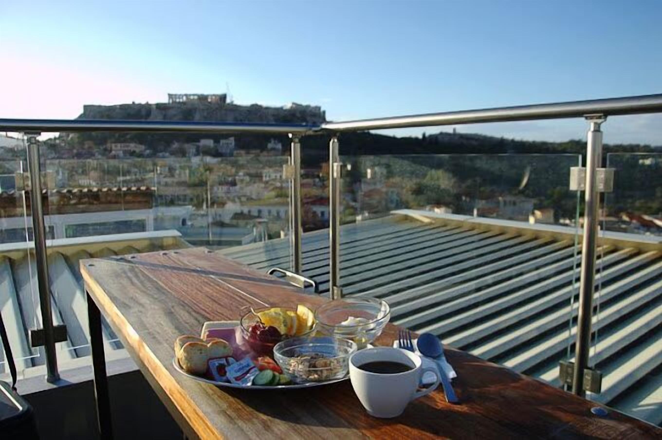 A dining table on a rooftop with a city view, a tray with food and a cup of coffee.