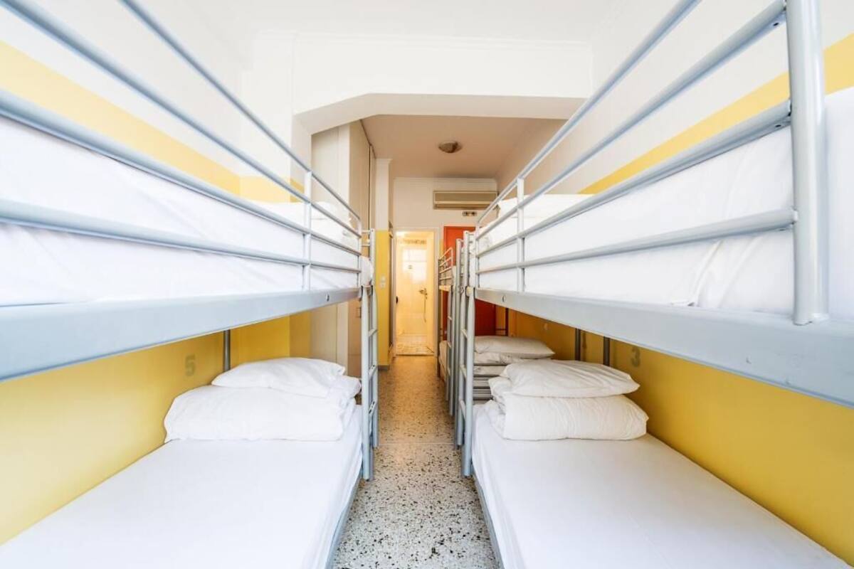 Un pasillo estrecho con literas a ambos lados, que conduce a una puerta al final.