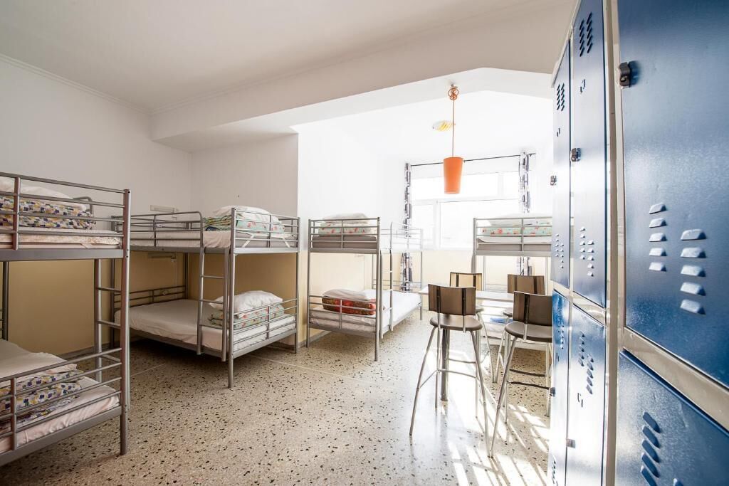 Un dormitorio con literas, un escritorio, sillas y taquillas.