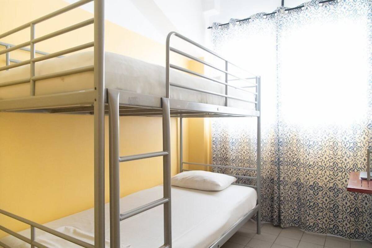 Habitación con literas, paredes amarillas y cortinas estampadas.