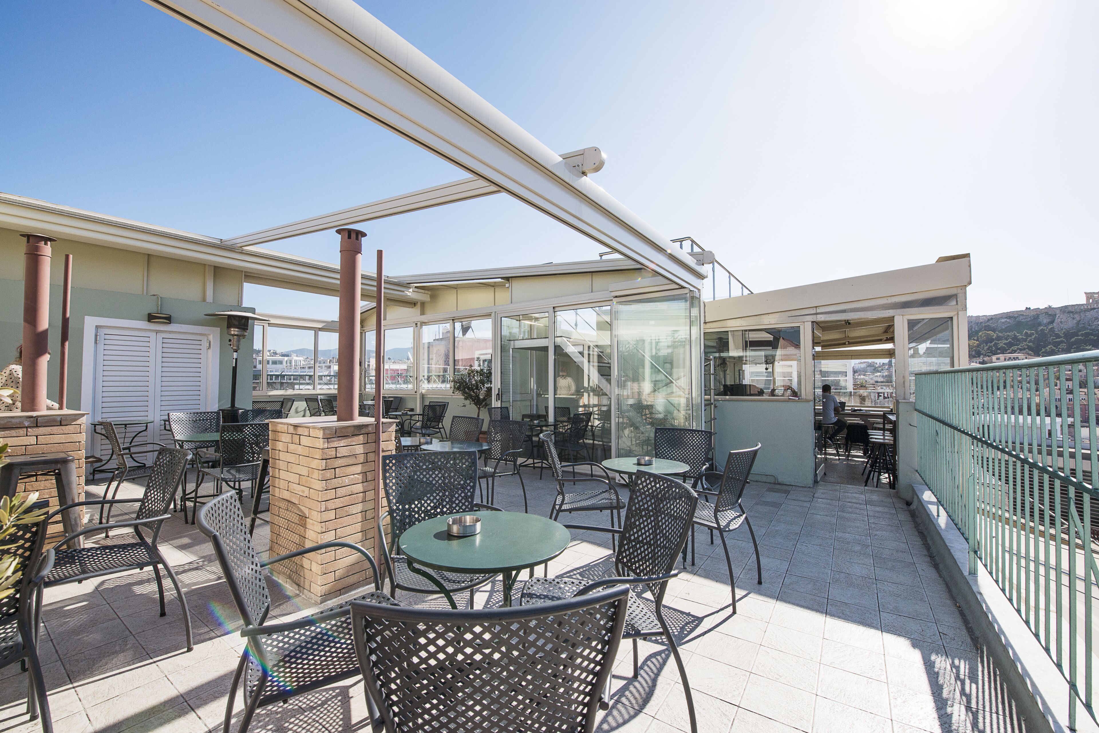 Un patio al aire libre con mesas y sillas, un pilar de ladrillo y un cerramiento de vidrio.