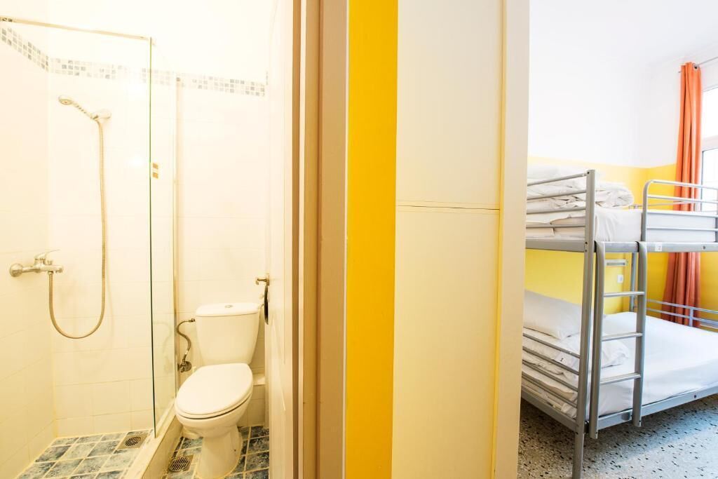 Un baño con ducha, inodoro y una litera con toallas dobladas.