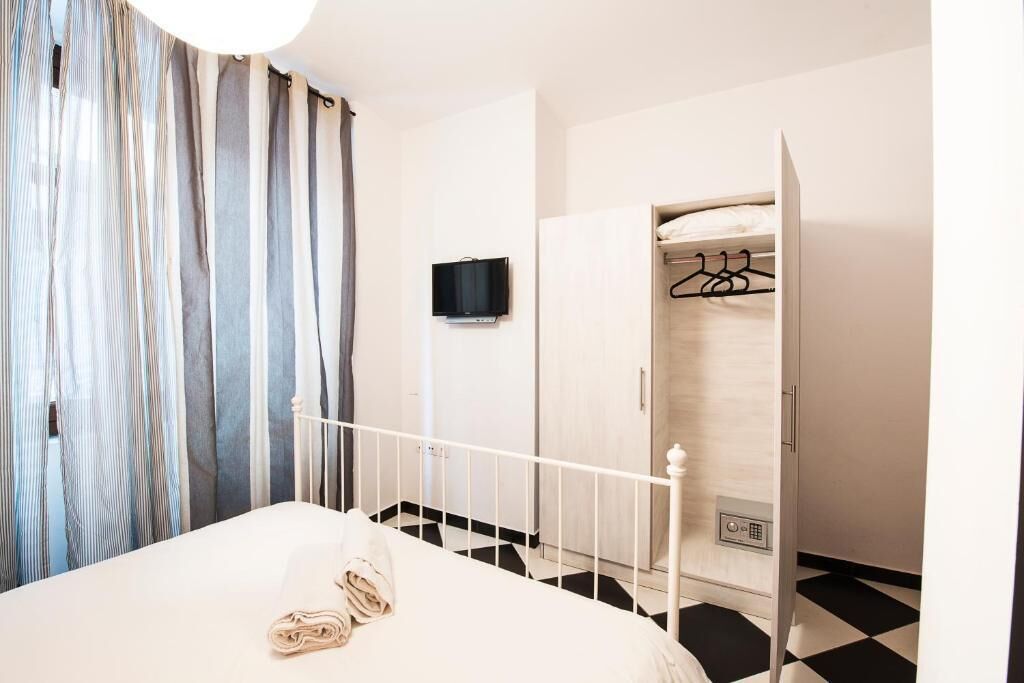 A hotel room with a bed, a television, a wardrobe, and a shower area.