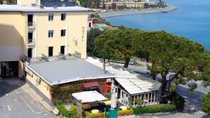 A hotel with a terrace, outdoor seating, and a view of the sea. - Hotel Puntabella (Varazze)