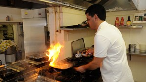 A chef cooking on a stovetop with flames visible. - Hotel Puntabella (Varazze)