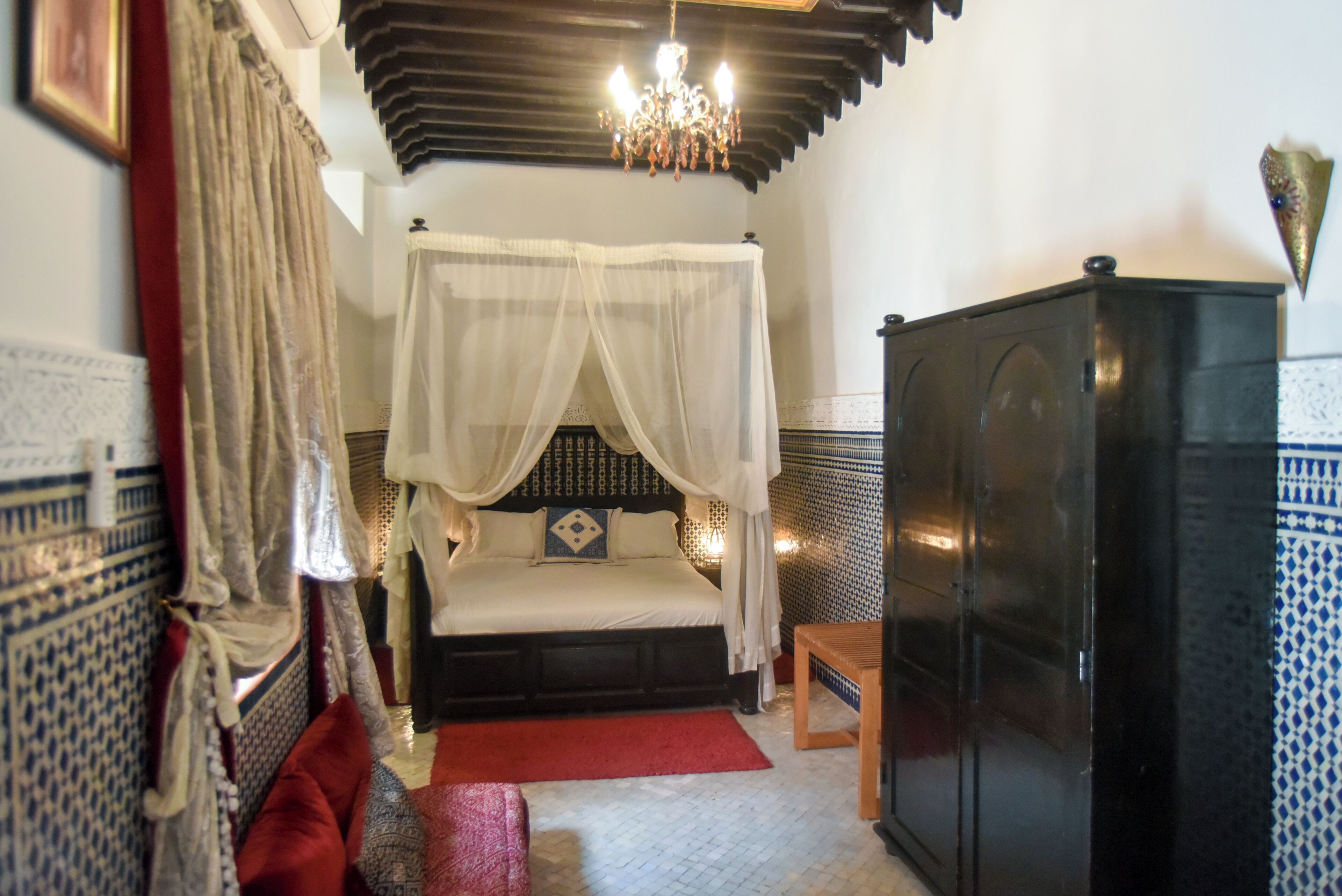 Une chambre à coucher comprenant un lit, une table de chevet, une armoire et un lustre.