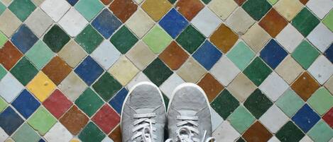 Un par de zapatillas grises sobre un suelo de mosaicos de colores.