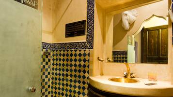 Un baño con lavabo, espejo y azulejos estampados.