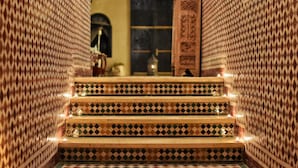 Una escalera con baldosas decoradas que conduce a una habitación con un gran armario de madera y una pequeña mesa.