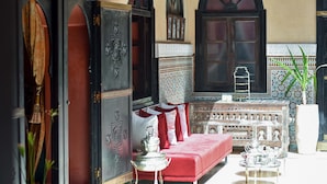 Una habitación con un sofá rojo, un aparador decorativo y una ventana con vistas al exterior.