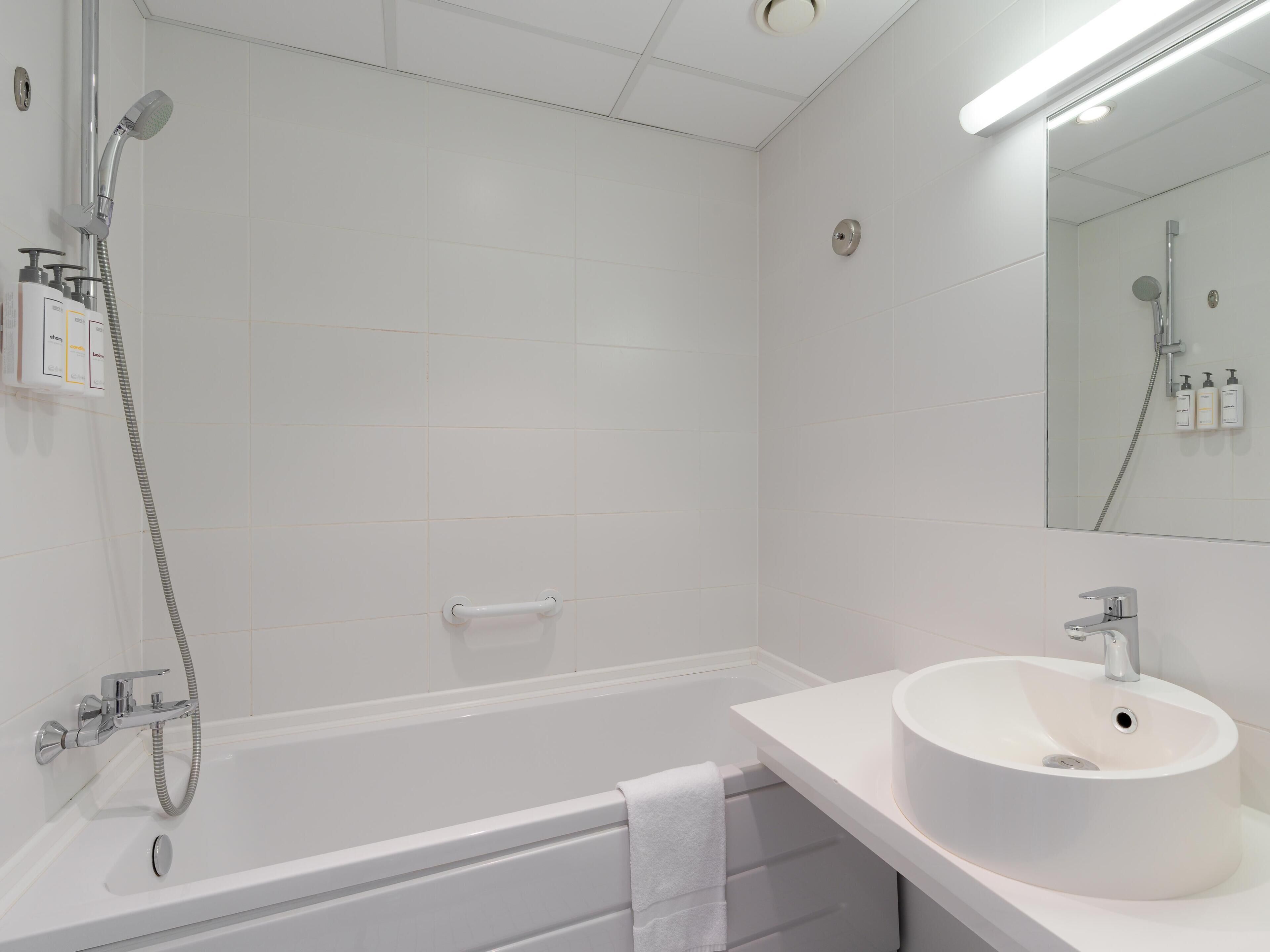 A modern bathroom with a bathtub, a sink, a shower, and a mirror.