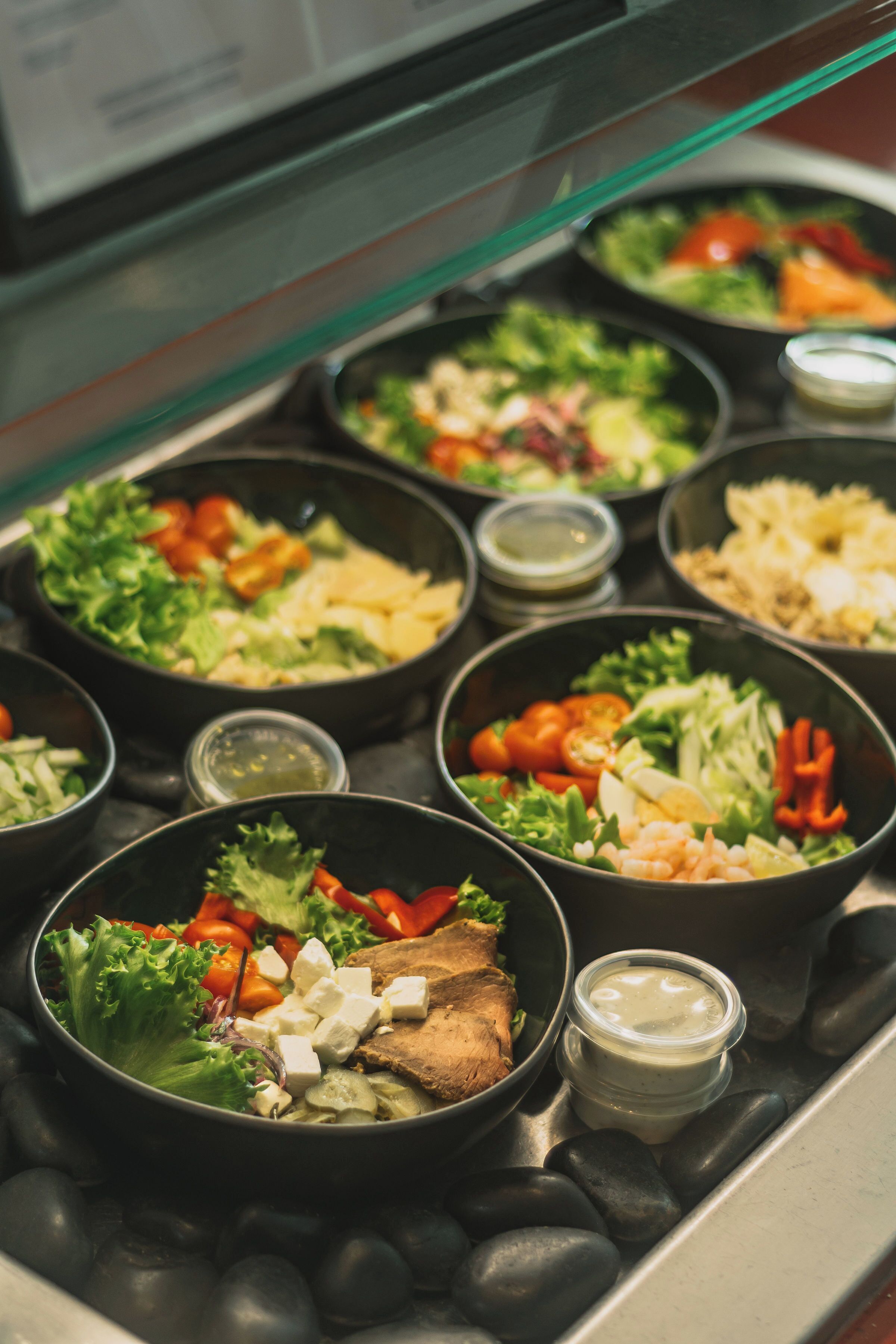 A buffet with various dishes including salads, meats, and cheeses.